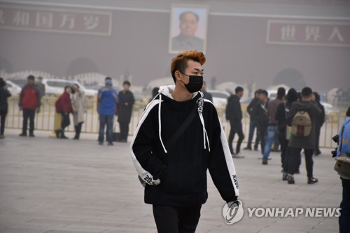 지난 14일 베이징의 한 시민이 거리를 걷고 있다. (사진 = 연합뉴스)