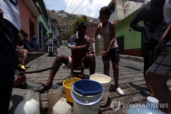 길거리 소화전에서 물을 받는 카라카스 시민 [EPA=연합뉴스 제공]