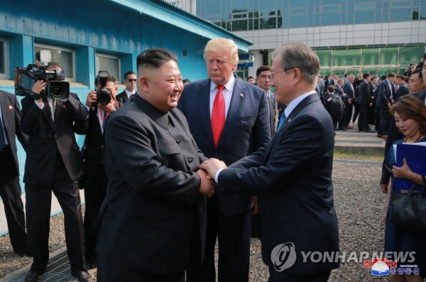 문재인 대통령과 김정은이 6월 30일 오후 판문점에서 두손을 맞잡고 대화하고 있다. 가운데는 도널드 트럼프 미국 대통령(연합뉴스)
