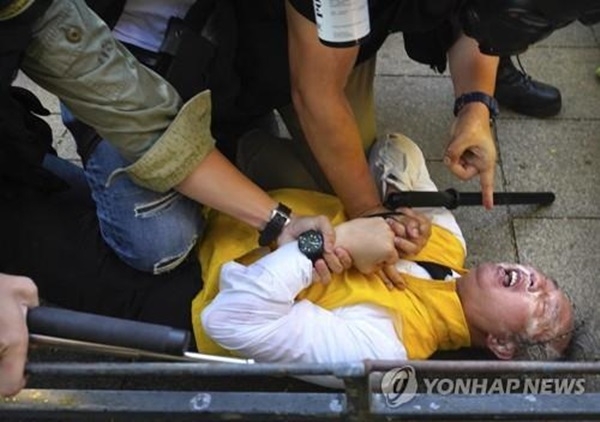 지난 11월2일(현지시간) 중국공산당 반대-자유화 시위 도중 경찰에 체포된 구의원 선거 후보 리차드 찬이 최루액에 맞고 괴로워하고 있는 모습.(사진=연합뉴스)