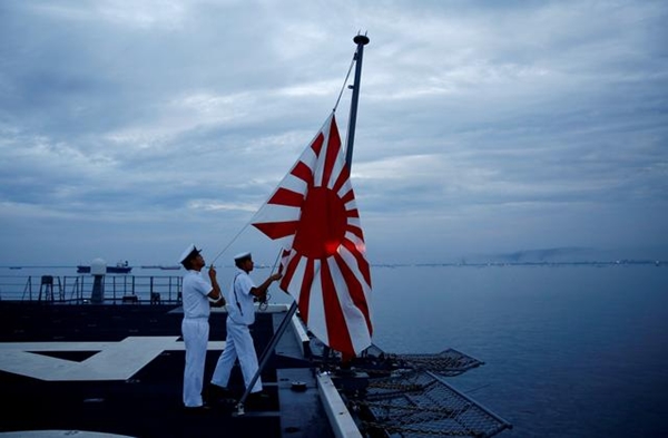 일본 해상자위대 경항공모함 가가(加賀)의 승조원들이 자위함기(욱일기)를 내리고 있다.(사진=로이터)