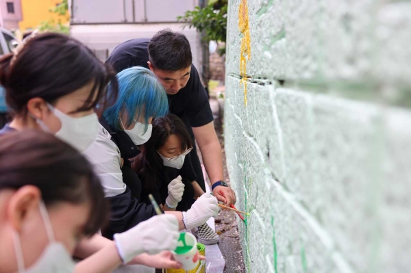 경남정보대학교 시각디자인학과 학생들이 부산 사상구 괘내마을의 노후 옹벽에 벽화글 그리는 봉사를 하고 있다. [경남정보대 제공]