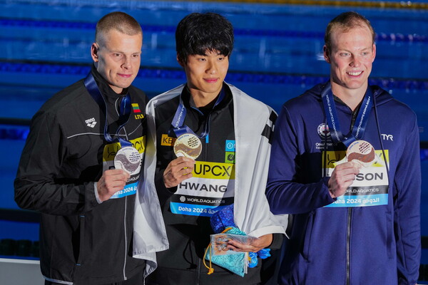 황선우(가운데)가 14일(한국시간) 카타르 도하 어스파이어돔에서 열린 2024 국제수영연맹 세계선수권대회 경영 남자 자유형 200ｍ 결승에서 우승한 뒤, 시상식에서 2위 랍시스(왼쪽), 3위 홉스와 기념 촬영하고 있다. [AP연합]