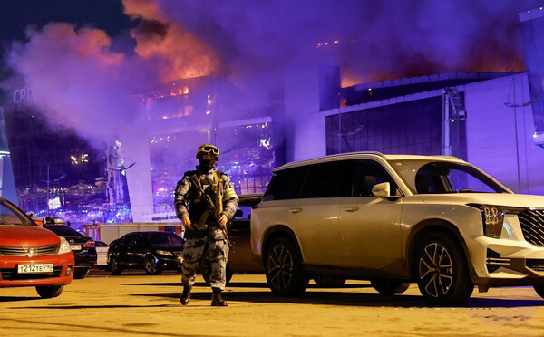 22일(현지시간) 무차별 총격 사건이 벌어진 러시아 모스크바 외곽 대형 콘서트장에서 화염이 치솟고 있다. 외부에는 구급차가 부상자를 이송하기 위해 대기 중이다. [로이터연합]
