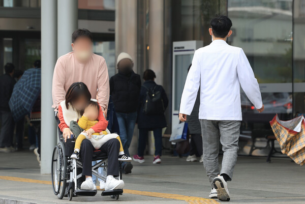 전국 의과대학 교수들의 집단 사직이 가시화하는 가운데 19일 서울 시내 한 대학병원에서 한 환자가족이 의료진을 등진 채 이동하고 있다. [연합뉴스]